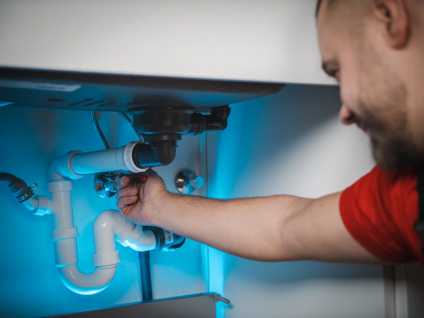 Plombier réparant une canalisation sous un évier